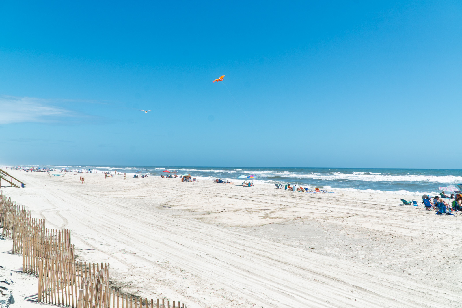 Wide open Atlantique beach with umbrellas, family with cooler in foreground